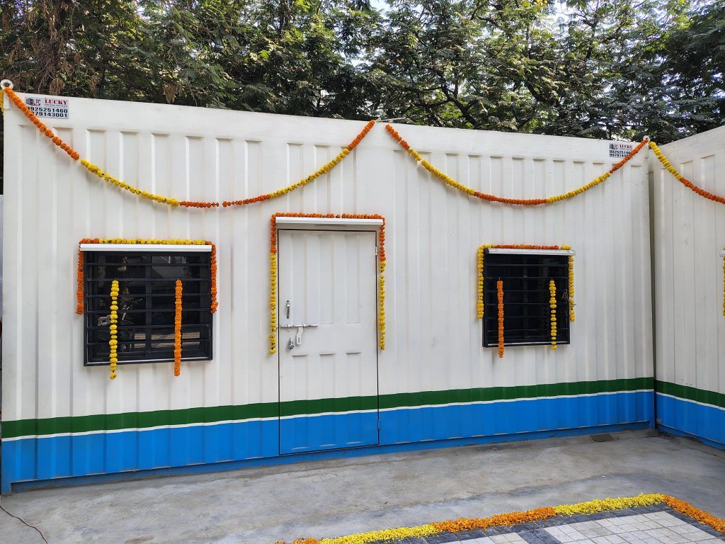 A white container house decorated with marigold garlands.