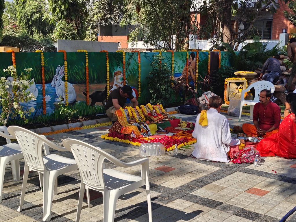 A pooja ceremony taking place at the Kalyan Jivashray Foundation, with people offering prayers and flowers.